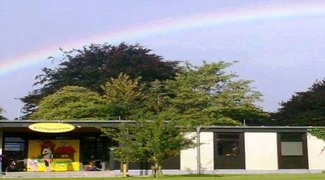 Der Eingangsbereich der Kita von außen, darüber ein Regenbogen