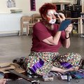 Eine Frau hat sich als Clown geschminkt. Sie sitzt auf dem Boden.