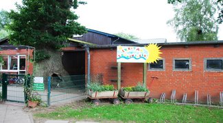 bepflanzte hölzerne Bollerwagen unter einem Schild "Ev. Kita Sonnenschein"