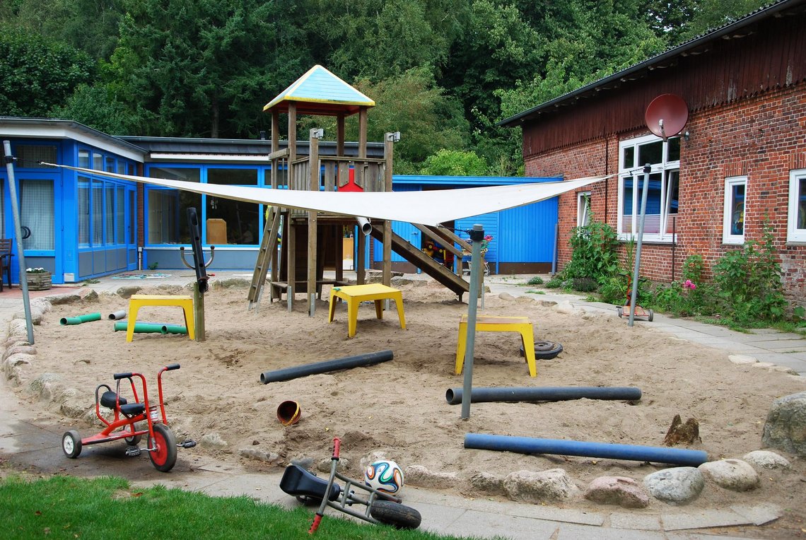 Außenspielbereich Sand mit Sonnensegel und Röhren