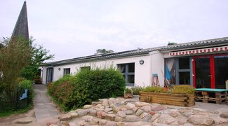 Außenspielbereich mit Kirchturm im Hintergrund