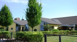 Hellgelbes Kitagebäude im Sonnenschein